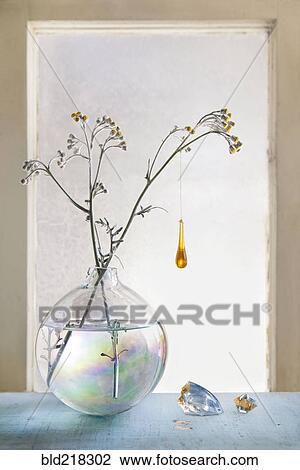 Stock Image - Glass ornament hanging from plants in glass vase. Fotosearch