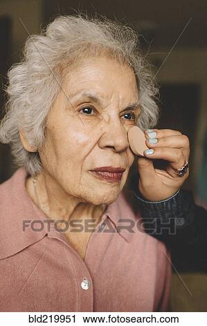 Stock Image - Granddaughter applying makeup on grandmother. Fotosearch