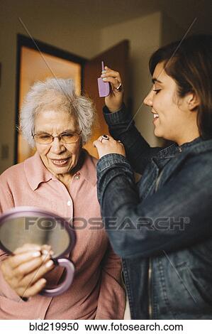 Granddaughter combing hair of grandmother holding mirror View Large Photo Image Stock Image - Granddaughter combing hair of grandmother holding mirror. Fotosearch