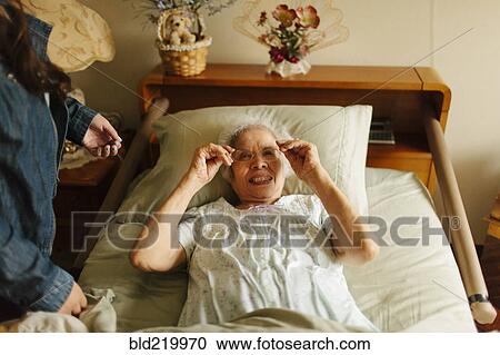 Granddaughter giving grandmother eyeglasses in bed View Large Photo Image Stock Image - Granddaughter giving grandmother eyeglasses in bed. Fotosearch