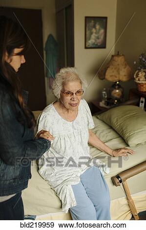 Stock Photo - Granddaughter helping grandmother out of bed. Fotosearch