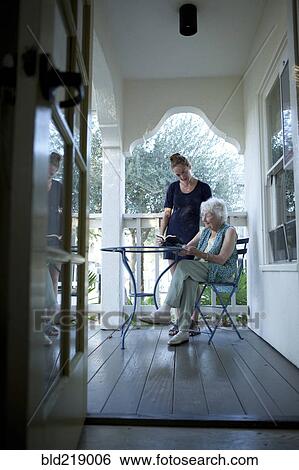 Stock Photograph - Granddaughter talking to grandmother on porch. Fotosearch