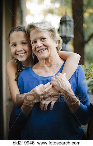 Stock Photograph - Grandmother and granddaughter hugging on porch. Fotosearch