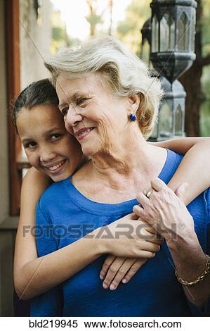 Stock Photography - Grandmother and granddaughter hugging on porch. Fotosearch