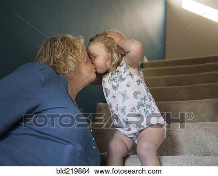 Picture - Grandmother and granddaughter kissing on staircase. Fotosearch