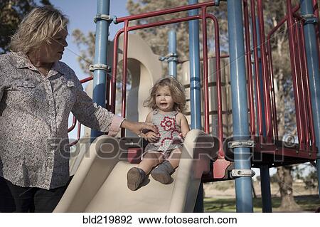 Stock Image - Grandmother and granddaughter playing at playground. Fotosearch