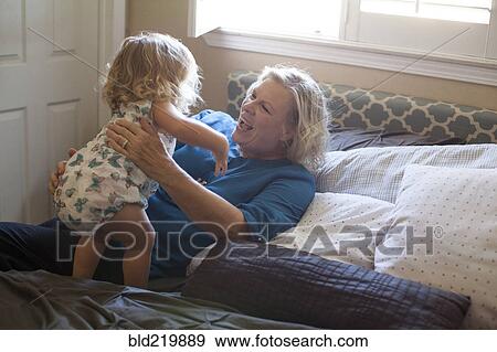 Grandmother and granddaughter playing on bed View Large Photo Image Stock Photo - Grandmother and granddaughter playing on bed. Fotosearch