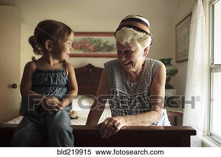 Stock Photography - Grandmother and granddaughter playing on bed. Fotosearch