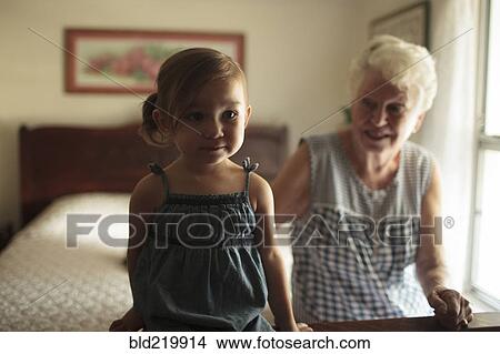 Grandmother and granddaughter sitting on bed View Large Photo Image Picture - Grandmother and granddaughter sitting on bed. Fotosearch