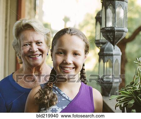 Stock Image - Grandmother and granddaughter smiling on porch. Fotosearch