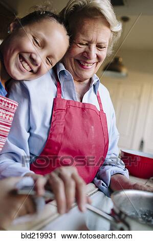 Stock Image - Grandmother and granddaughter using kitchen sink. Fotosearch