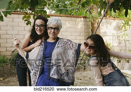 Stock Image - Grandmother and granddaughters playing in backyard. Fotosearch