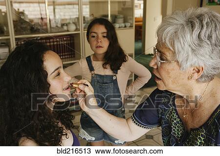 Grandmother applying lipstick to granddaughter in dining room View Large Photo Image Stock Image - Grandmother applying lipstick to granddaughter in dining room. Fotosearch