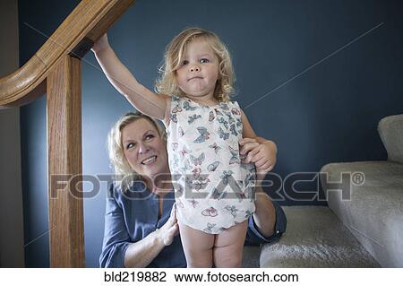 Stock Image - Grandmother helping granddaughter on staircase. Fotosearch