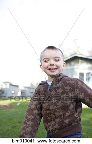 Stock Image - Grinning Caucasian boy playing in yard. Fotosearch