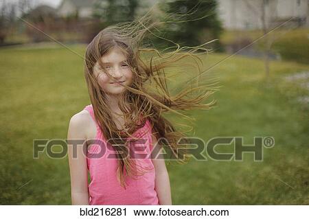 Stock Image - Hair of Caucasian girl blowing in wind in backyard. Fotosearch