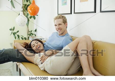 Stock Image - Happy couple relaxing on sofa. Fotosearch