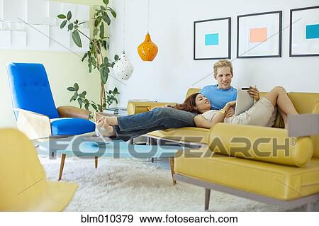 Happy couple relaxing on sofa with digital tablet View Large Photo Image Stock Photo - Happy couple relaxing on sofa with digital tablet. Fotosearch