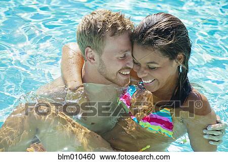 Stock Image - Happy couple swimming in swimming pool. Fotosearch