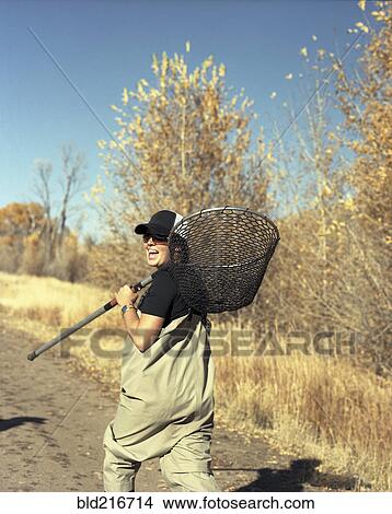 Picture - Happy woman carrying fishing net on dirt path. Fotosearch