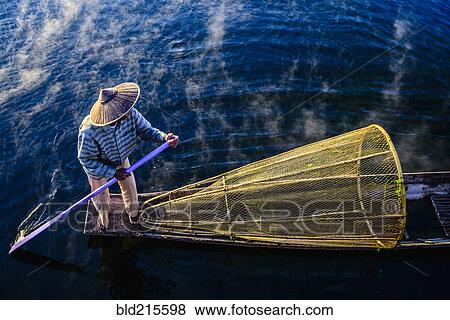 Stock Photo - High angle view of Asian fisherman using fishing net in canoe on river. Fotosearch
