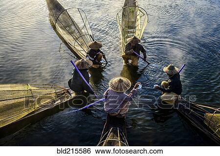 Stock Photograph - High angle view of Asian fishermen fishing in canoes on river. Fotosearch