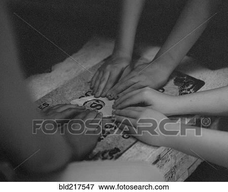 Stock Photo - High angle view of children playing with ouija board. Fotosearch