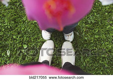 Stock Photography - High angle view of feet of mother and daughter in grass. Fotosearch