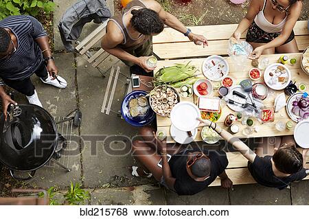 Stock Photo - High angle view of friends eating at backyard barbecue. Fotosearch
