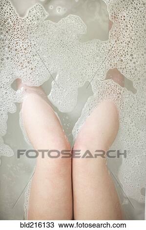 Stock Image - High angle view of legs of woman soaking in bathtub. Fotosearch