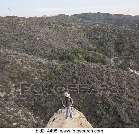 Stock Photography - High angle view of older Caucasian man standing on rocky hilltop. Fotosearch