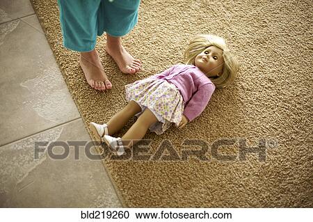 Stock Image - High angle view of teenage girl standing over doll. Fotosearch