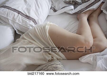 Stock Image - High angle view of woman laying in bed. Fotosearch