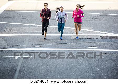 Stock Image - High angle view of women running in city street. Fotosearch