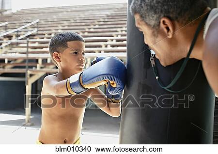Stock Image - Hispanic boy boxing punching bag. Fotosearch