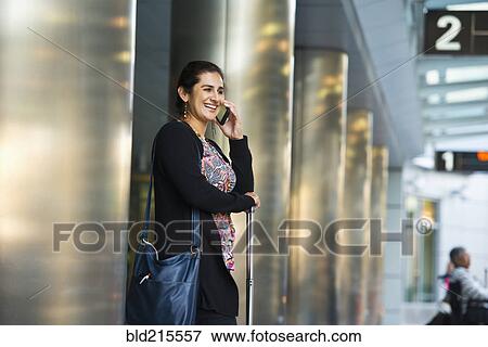 Stock Photo - Hispanic businesswoman talking on cell phone in airport. Fotosearch