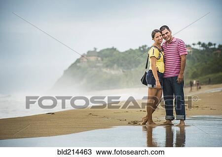 Hispanic couple hugging in waves on beach View Large Photo Image Stock Image - Hispanic couple hugging in waves on beach. Fotosearch