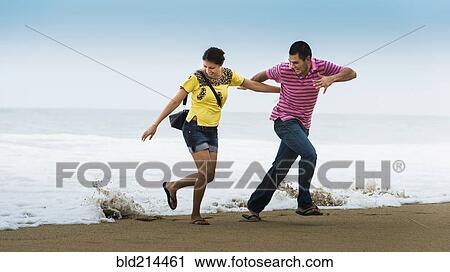 Hispanic couple playing near waves on beach View Large Photo Image Stock Image - Hispanic couple playing near waves on beach. Fotosearch