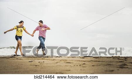 Hispanic couple running in waves on beach View Large Photo Image Picture - Hispanic couple running in waves on beach. Fotosearch