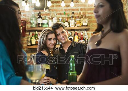 Picture - Hispanic couple smiling in bar. Fotosearch