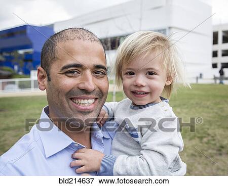 Stock Photo - Hispanic father and son smiling in field. Fotosearch