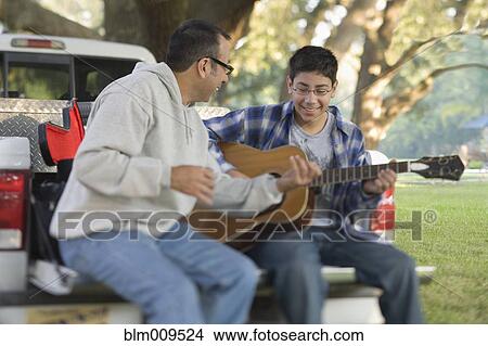Hispanic father teaching son to play guitar View Large Photo Image Picture - Hispanic father teaching son to play guitar. Fotosearch