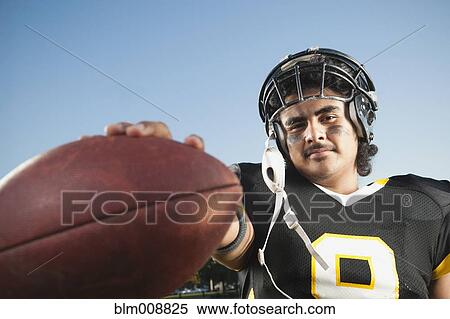 Stock Photography - Hispanic football player holding football. Fotosearch