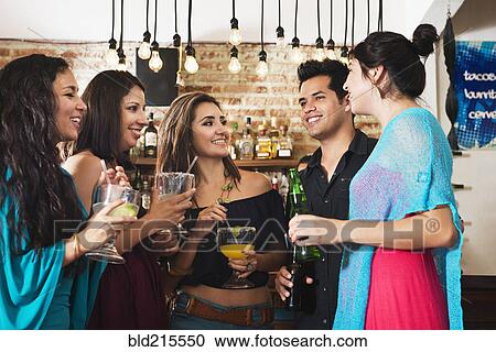 Stock Image - Hispanic friends having drink in bar. Fotosearch