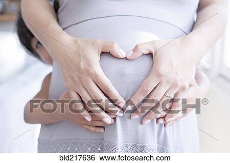 Stock Photograph - Hispanic girl holding belly of pregnant mother. Fotosearch