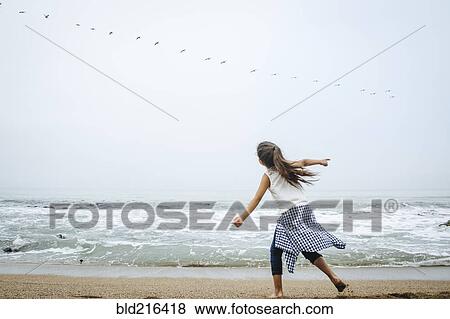 Stock Photo - Hispanic girl playing on beach. Fotosearch