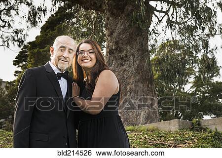 Stock Photograph - Hispanic grandfather and granddaughter smiling in formal wear. Fotosearch