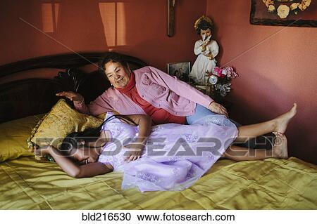 Hispanic grandmother and granddaughter laying on bed View Large Photo Image Stock Image - Hispanic grandmother and granddaughter laying on bed. Fotosearch