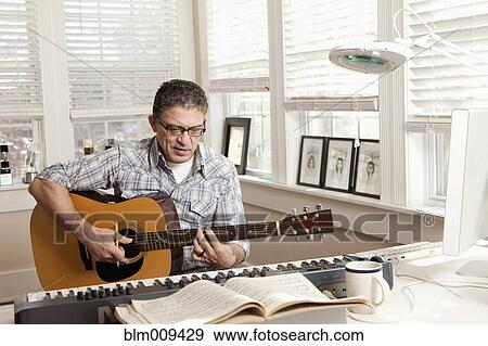 Stock Photo - Hispanic man composing music on guitar. Fotosearch