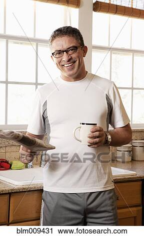 Stock Image - Hispanic man drinking coffee and reading newspaper. Fotosearch